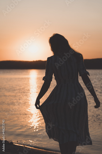 Woman standing at the beach on sunset in dress © Anton Tolmachov