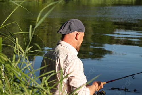 Man in a white shirt and hat fishing at the lake