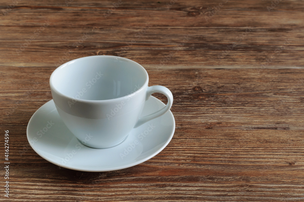 Empty white porcelain cup and saucer on wooden table. Copy space Empty white porcelain cup and saucer on wooden table. Copy space