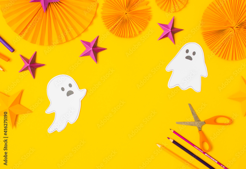 Fototapeta premium Halloween paper craft flat lay.Children seasonal art table top view.Kids hand craft concept.Bright halloween background with cutted out ghosts and paper crafts.