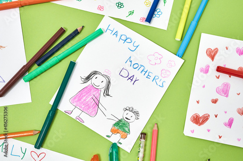 Happy mothers day. Colorful child drawings and felt tip pens lying on green table