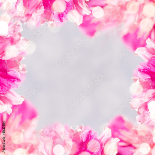 Square frame of gentle pink peonies petals and bokeh lights and copy space for text on light grey. © SeNata