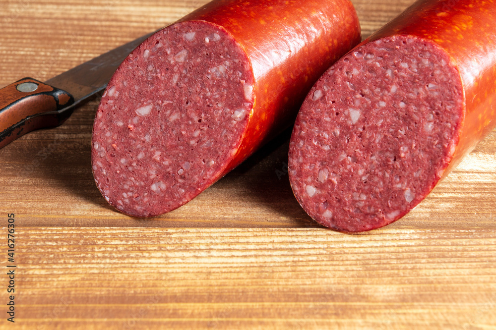 Sliced salami sausage and knife on cutting board closeup. Food preparation idea before the holiday Sliced salami sausage and knife on cutting board closeup. Food preparation idea before the holiday