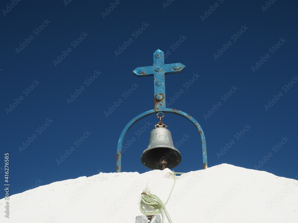 Old blue metal cross and bell on traditional Greek church