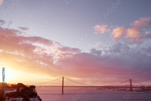 Beautiful landscape with suspension 25 April bridge bridge over the Tagus river in Lisbon at sunset.