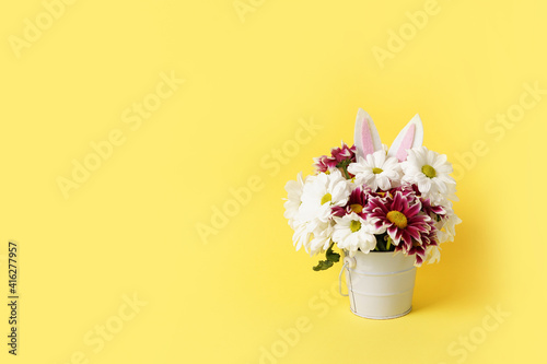 Fototapeta Naklejka Na Ścianę i Meble -  easter spring flowers with rabbit ears on yellow background, copy space