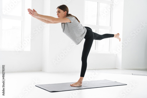 Fototapeta Naklejka Na Ścianę i Meble -  Athletic pleased sportswoman doing exercise during yoga practice