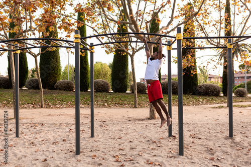 Fotografie african american athlete doing fitness exercises on bars, calisthenics workout