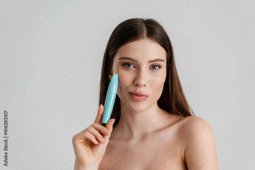 Pleased shirtless girl looking at camera while posing with mascara Pleased shirtless girl looking at camera while posing with mascara