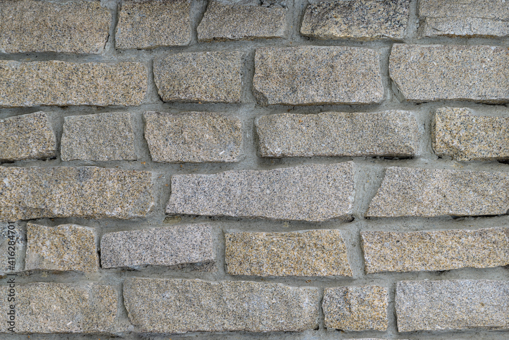 Obraz premium natural stone masonry using cement. textured natural surface. Front wall of the building, stone trim with ragged edges 