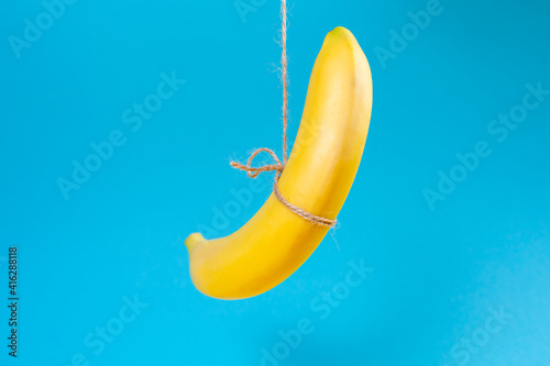 The concept of the problem of suicide and crime. A banana hung on a rope. Blue background. Copy space