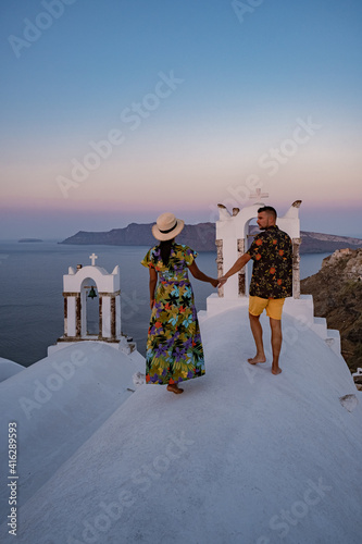 Santorini Greece, young couple mid age European and Asian on vacation at the Greek village of Oia Santorini Greece, luxury vacation Santorini. mid age man and woman watching sunset Santorini photo