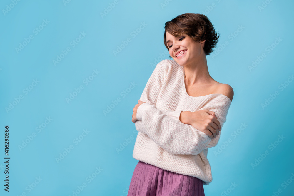 Photo of young girl happy positive smile hug herself comfort cozy look empty space isolated over blue color background