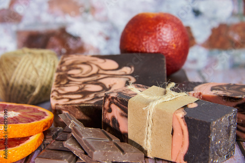 Natural handmade soap with chocolate and orange on a wooden countertop.