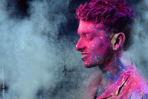 Portrait of a young man plays with Holi colours. Concept for Indian festival Holi 