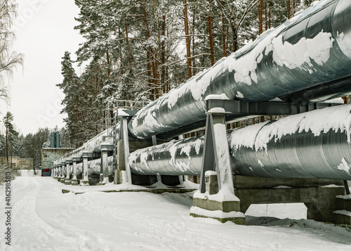 Huge industrial pipelines of central heating system. Snow on pipes. photo