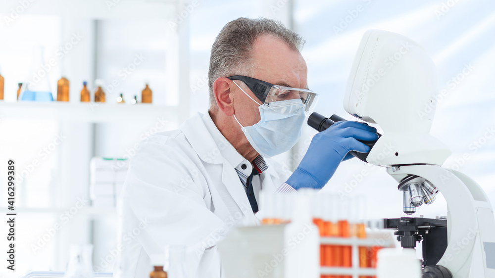 scientist in a protective mask conducts research in the laboratory. scientist in a protective mask conducts research in the laboratory.