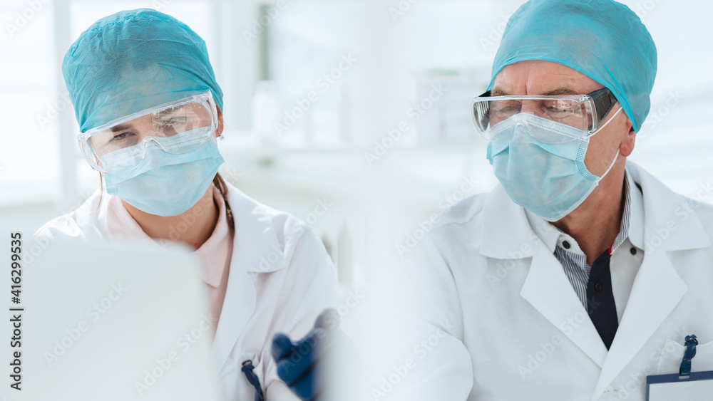 close up. scientists in laboratory masks looking at a computer monitor. close up. scientists in laboratory masks looking at a computer monitor.