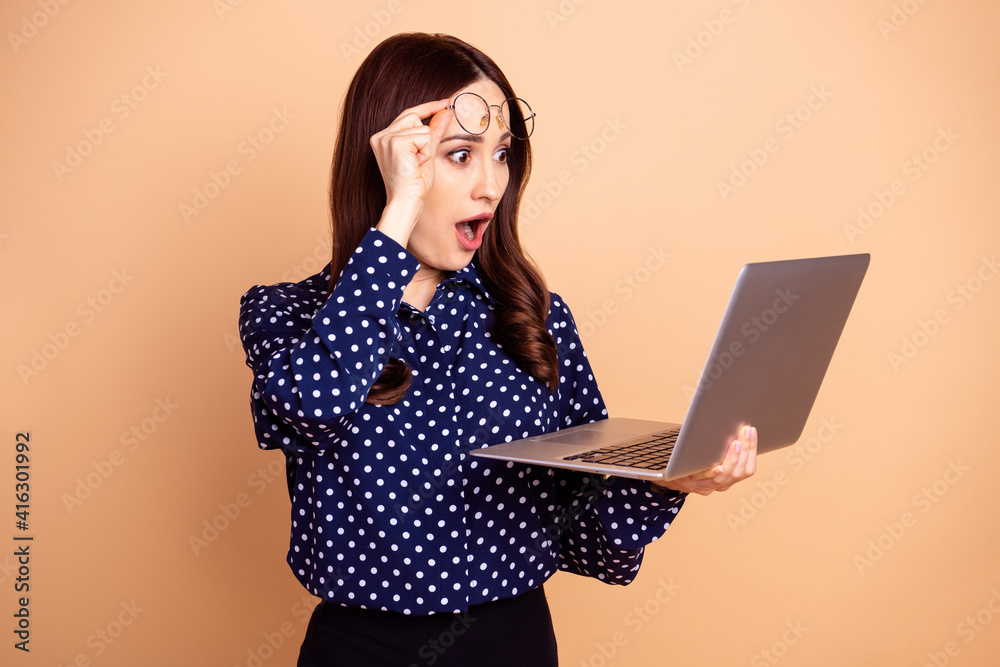 Naklejka premium Portrait of impressed pretty girl arm taking off eyewear open mouth look netbook isolated on beige color background