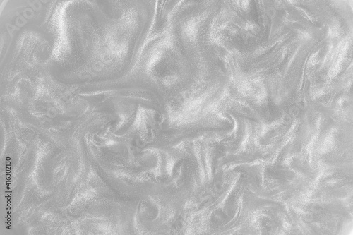 Silver paint background. Motion of the shiny liquid. Color of the year 2021 Ultimate Grey. Waves on a glittering liquid surface.