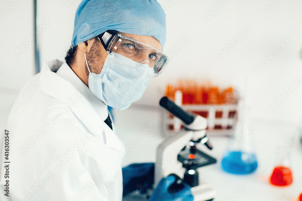 scientist looking at a drop of blood through a microscope. scientist looking at a drop of blood through a microscope.