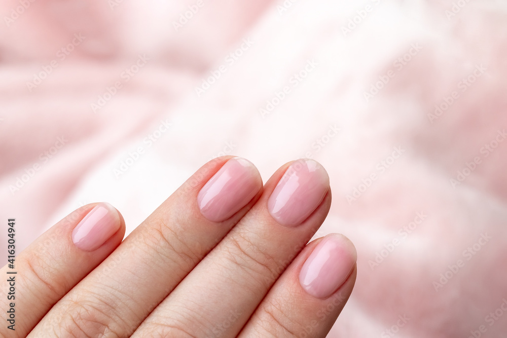 Female hands with beautiful manicure - pink nude nails on pale pink background, closeup with copy space. Selective focus Female hands with beautiful manicure - pink nude nails on pale pink background, closeup with copy space. Selective focus