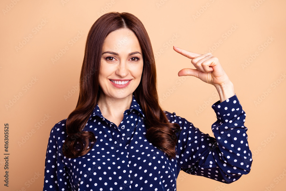 Photo of young cheerful woman happy smile show fingers little small tiny size measure isolated over beige color background Photo of young cheerful woman happy smile show fingers little small tiny size measure isolated over beige color background