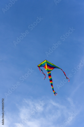 rainbow colored kite with a clear blue sky in the background