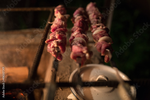 Fototapeta Naklejka Na Ścianę i Meble -  Meat with smoke on the barbecue grill. Fried meat of pork,beef, lamb on skewers are fried on fire, skewers on a metal skewer are grilled in the open air. Picnic concept