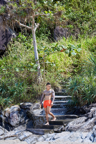 Athletic tattooed guy posing on staits at the jungles photo