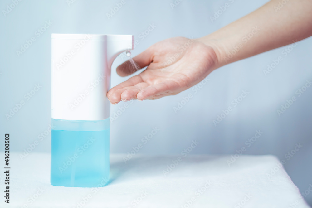 Close-up of women's hands using an automatic sanitizer dispenser Close-up of women's hands using an automatic sanitizer dispenser