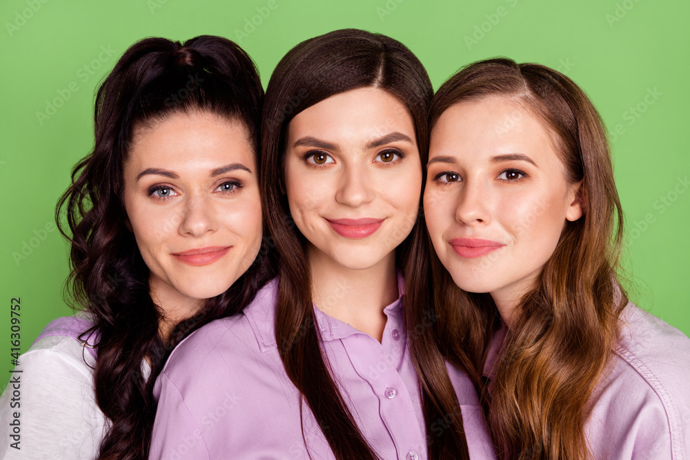 Photo of three young attractive girls happy positive smile girlfriends isolated over green color background Photo of three young attractive girls happy positive smile girlfriends isolated over green color background