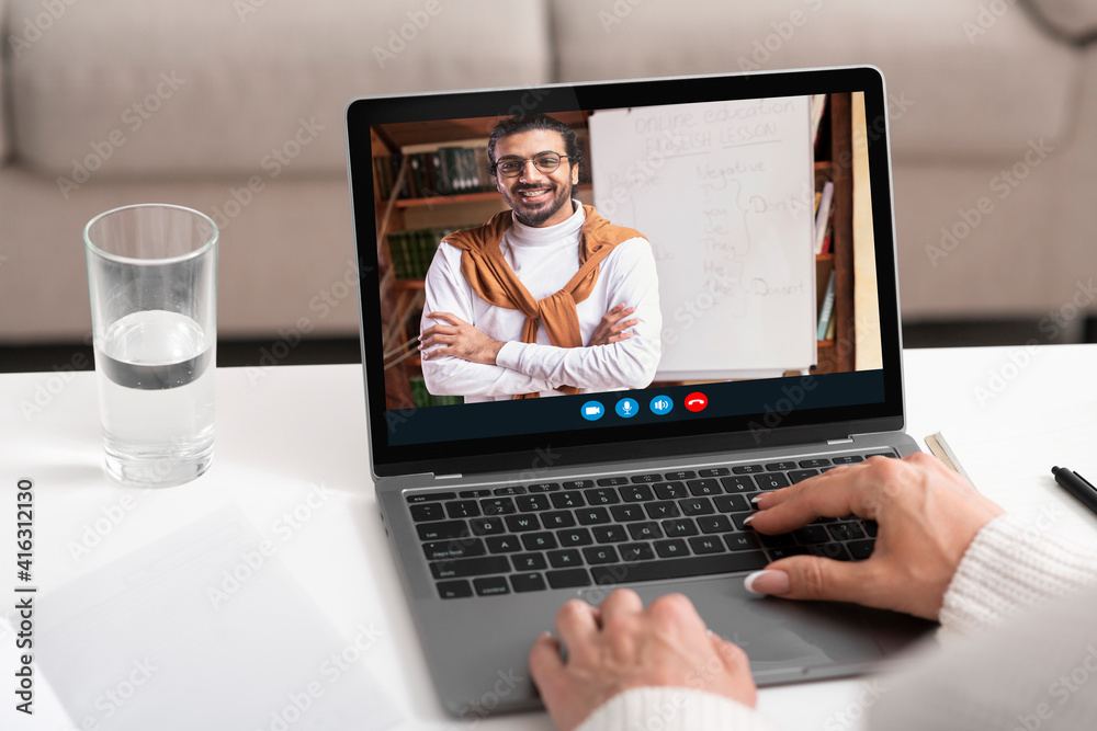Unrecognizable woman having online call with smiling middle-eastern teacher Unrecognizable woman having online call with smiling middle-eastern teacher