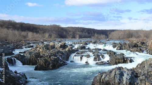 The large waterfall and rapids known as the Great Falls of the Potomac River as seen on a winter afternoon from Great Falls Park in Virginia. A static wide shot facing up the river.