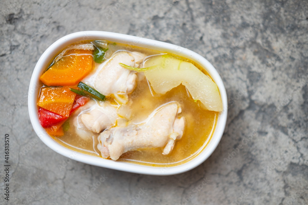 Boiled green soup winter melon with chicken drumsticks and carrot in a white ceramic bowl. Boiled green soup winter melon with chicken drumsticks and carrot in a white ceramic bowl.