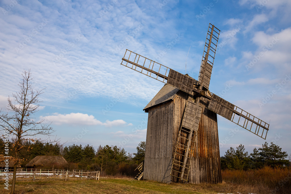 Wooden windmill in a rural open-air museum against the background of blue sky. Natural lighting conditions.
