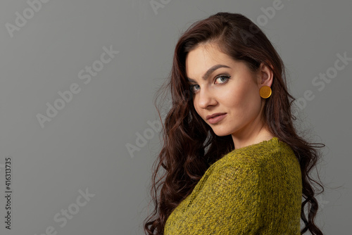 close-up portrait of beautiful sensual female with long curly hair against gray background