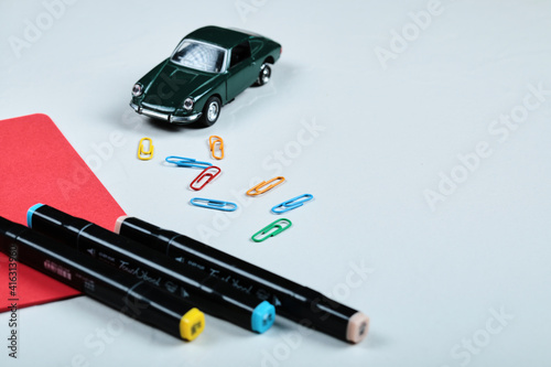 Colorful pencils, clips, red paper and toy car on white background © azerbaijan-stockers