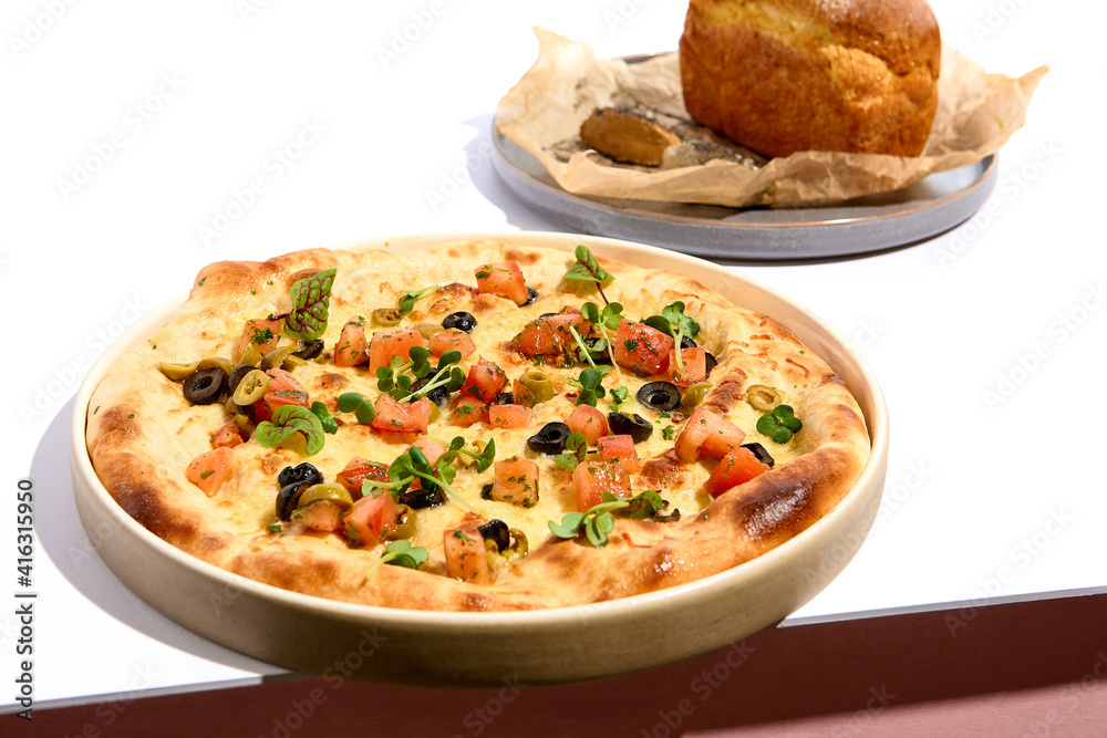 Olives and TOmato Focaccia and Cornbread on white table. White table and pink wall in sunlight with hard shadow. Summer day food concept. Olives and TOmato Focaccia and Cornbread on white table. White table and pink wall in sunlight with hard shadow. Summer day food concept.