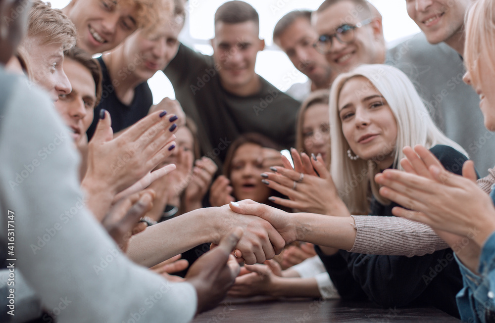 close up. handshake of young people to the applause of their friends. close up. handshake of young people to the applause of their friends.