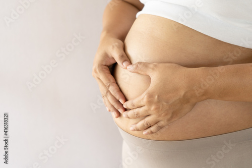 Pregnant women is happy and make hands heart shaped on fetus.