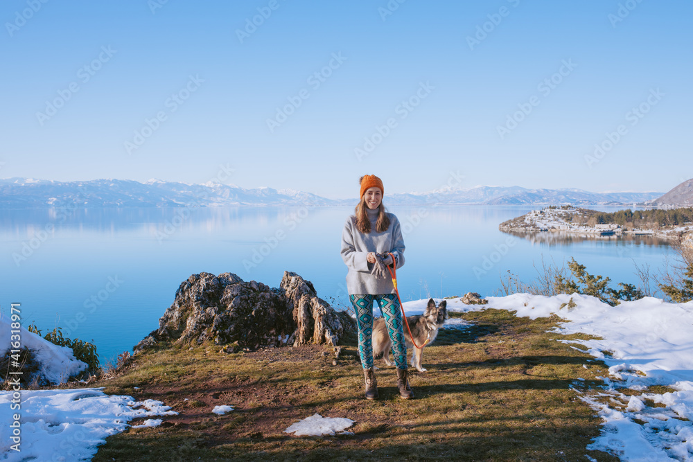 Woman walking her dog on a lake shore in winter