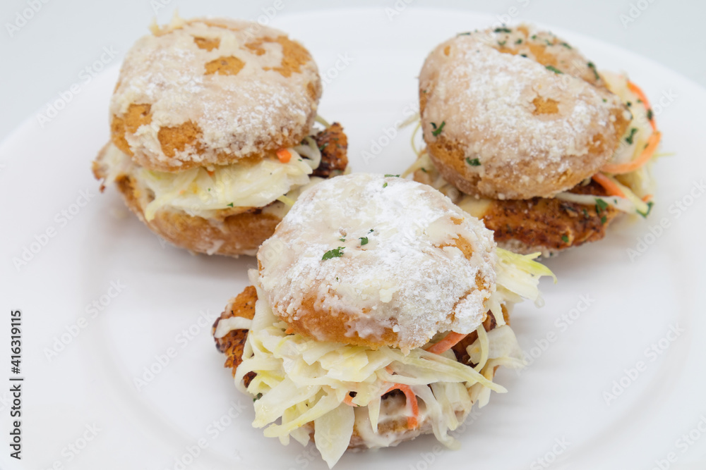 Three Delicious Chicken Beignet Sliders with Coleslaw on a White Plate Three Delicious Chicken Beignet Sliders with Coleslaw on a White Plate