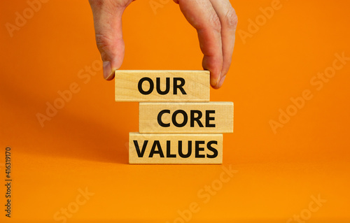 Our core values symbol. Concept words 'Our core values' on wooden blocks on a beautiful orange background, businessman hand. Business and our core values concept. Copy space. photo