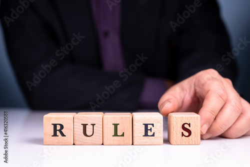Businessman arrange the wood blocks of RULES word