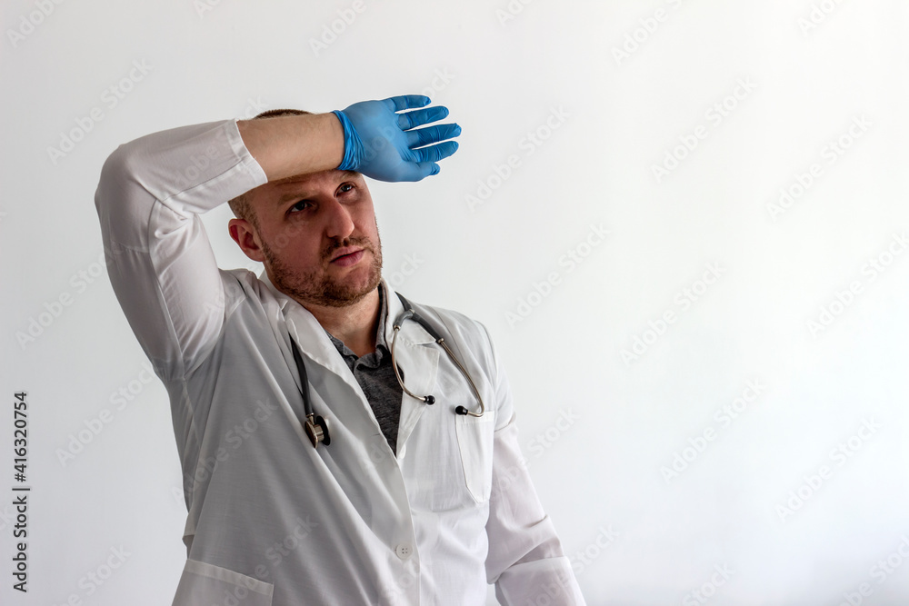 Tired Caucasian doctor or male nurse in white uniform and face medical mask for protection from virus disease isolated on white background. Exhausted doctor in uniform. Healthcare and medicine concept