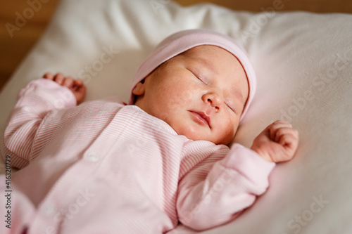 newborn baby of less than a week in a pink jumpsuit sleeps on a white plaid. Cute Little Close
