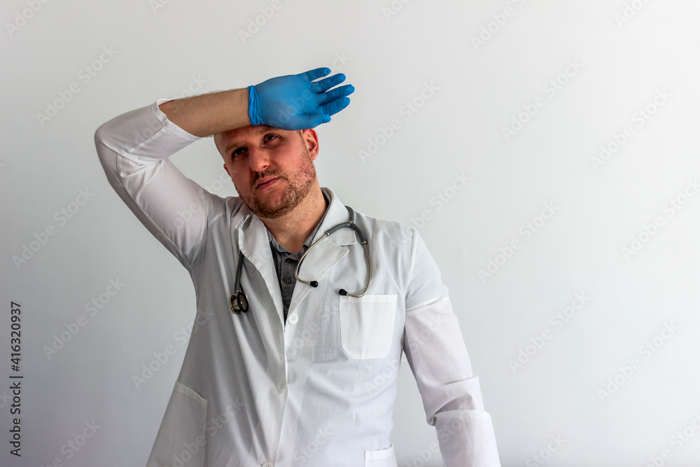 Tired Caucasian doctor or male nurse in white uniform and face medical mask for protection from virus disease isolated on white background. Exhausted doctor in uniform. Healthcare and medicine concept