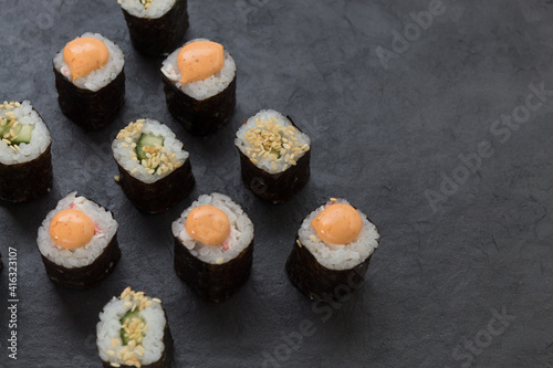 Rolls on a stone platter. Roll with cucumber, cheese sprinkled with sesame seeds. view from 45 degrees