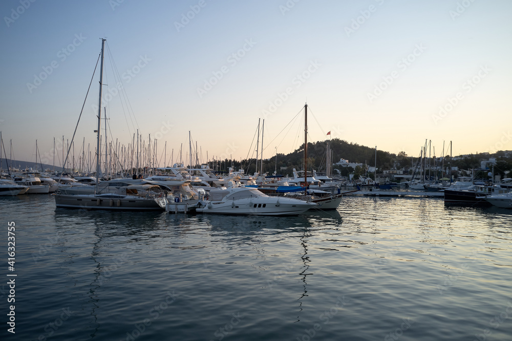 Landscape with boats in marina bay. Beautiful aegean sea with calm water, boats and yachts. Sunset sky in the background. Bodrum, Turkey.